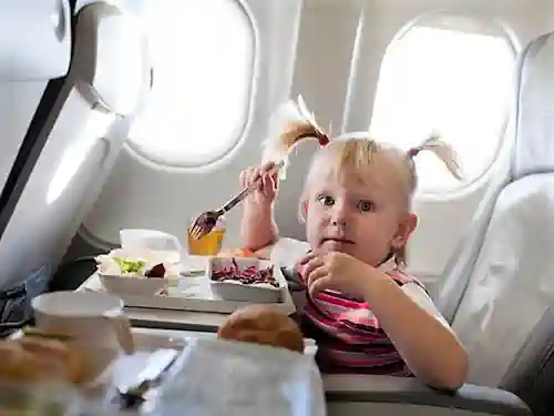 Niña comiendo en un asiento de avión